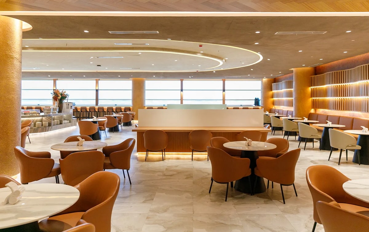 main seating area with dining tables, and large windows in the background.