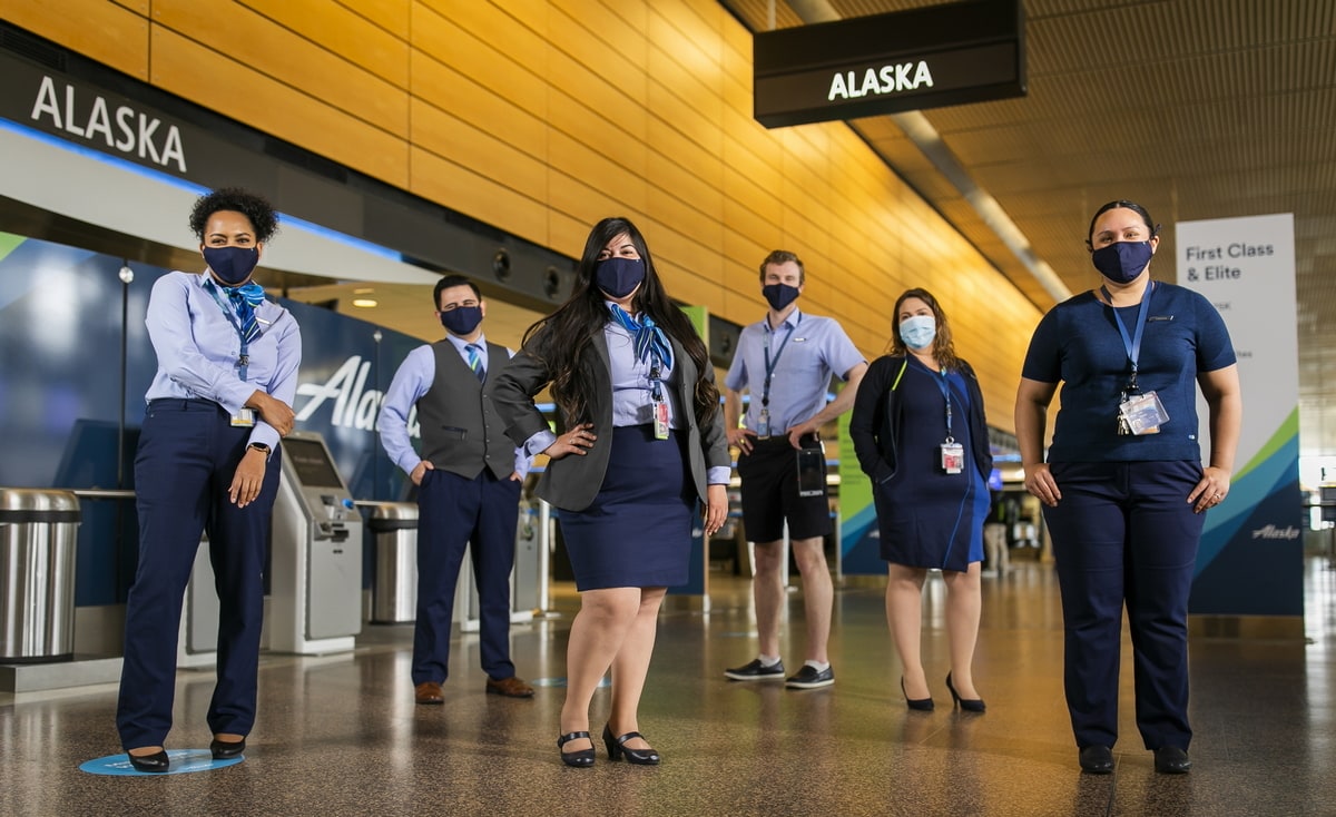 Alaska Airlines employees standing with masks on, in front of checkin.