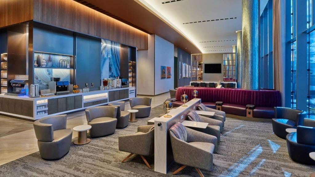 Inside view of the Delta Sky Club in Chicago showing chairs, tables, and a drink station.
