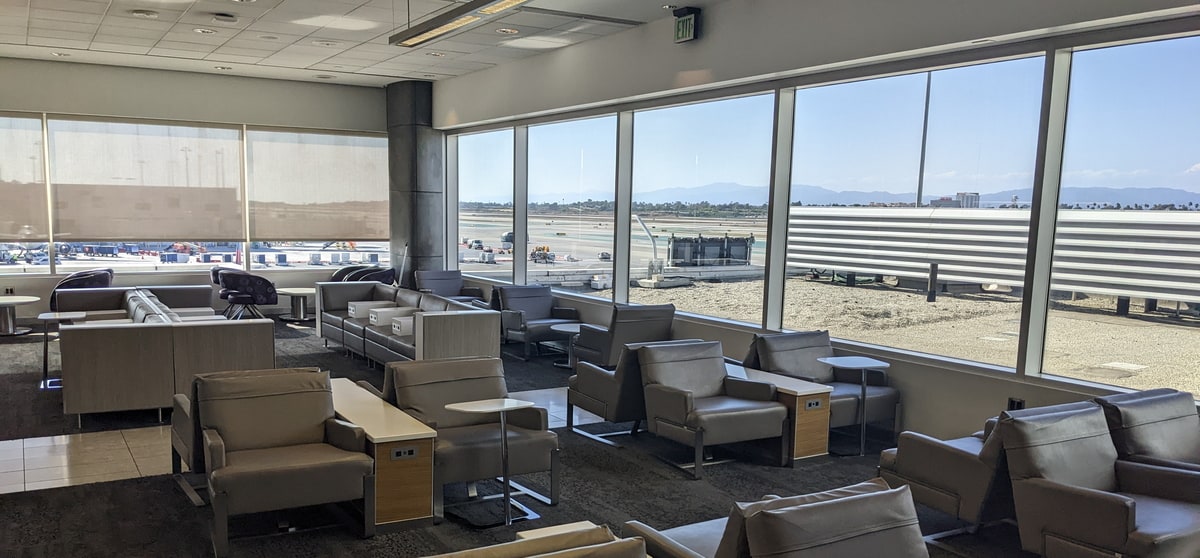 seating area in the corner of the lounge with large windows and view of runway.