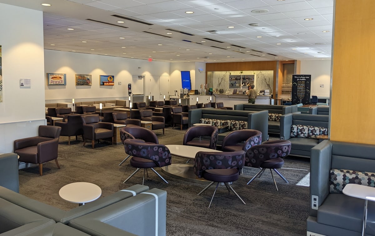 Inside the Delta Sky Club (LAX) Terminal 2, showing tables and chairs with only two people in the lounge.