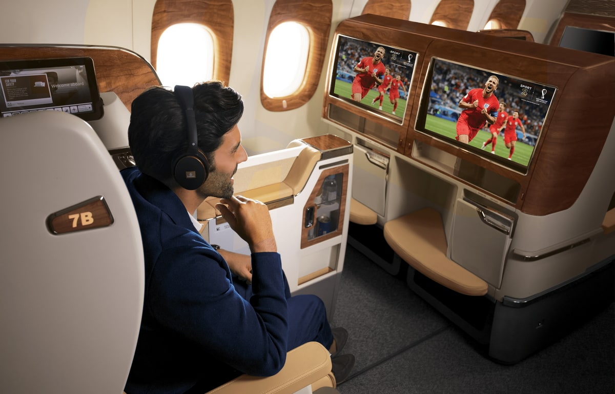 Person sitting in airplane, watching football on the seatback screen.