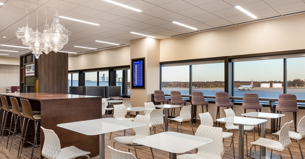 Rendering of the main dining area with tables and charis, and seats in large windows in the background.