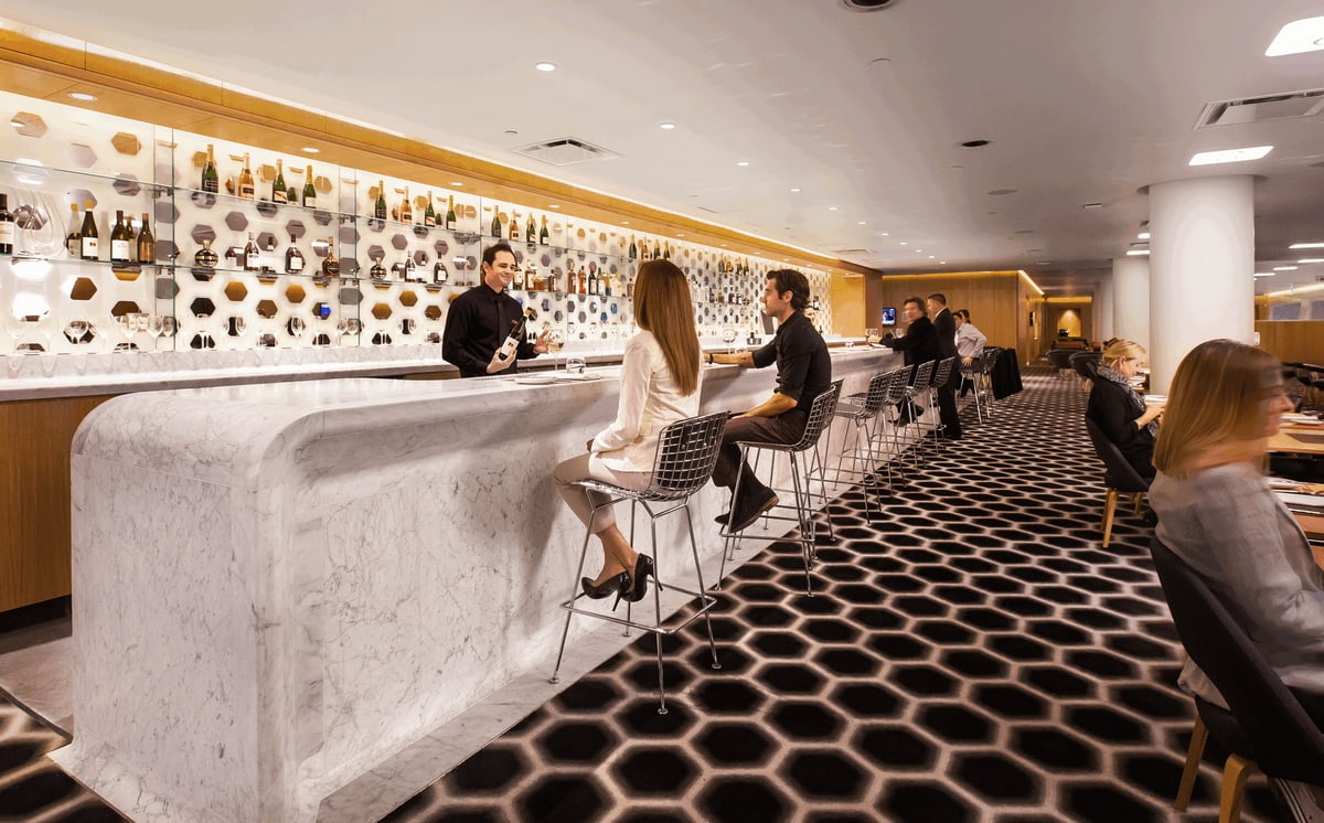 Bar area with people sitting at bar drinking wine.