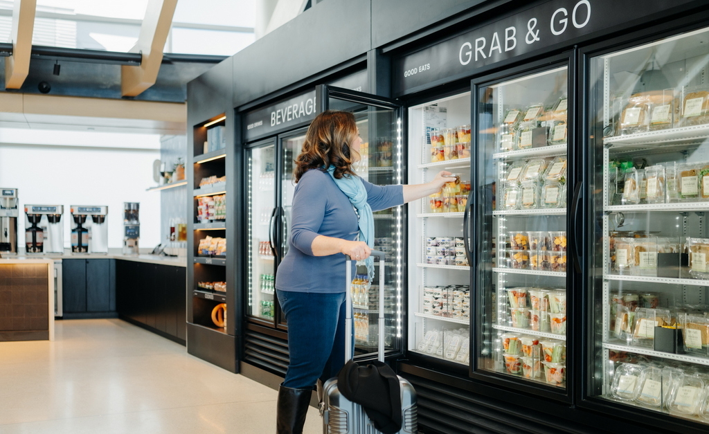 a person reaching into the fridge to get to-go food in packaged containers.