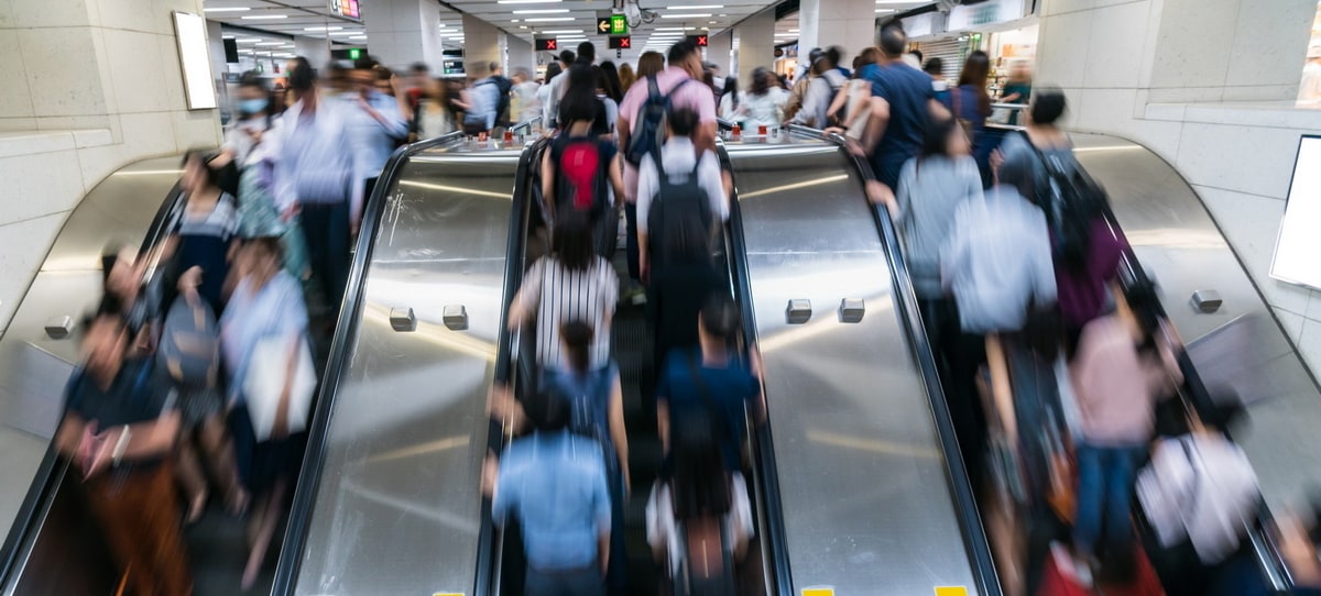 People on escalator in a crowded station.
