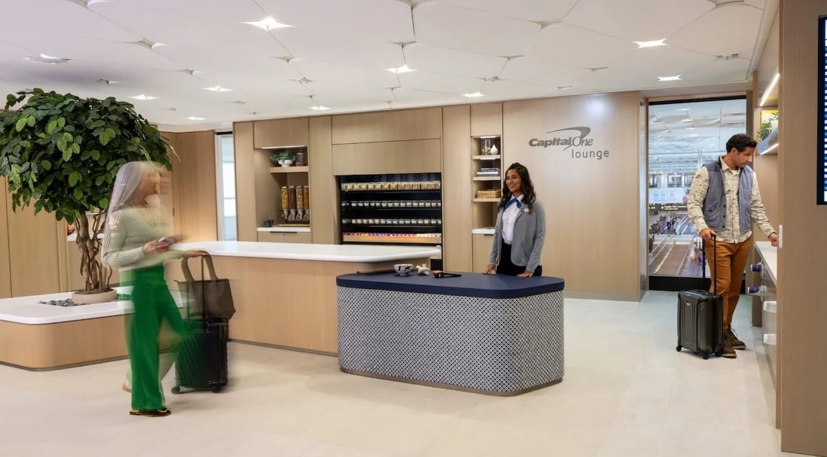 Check-in desk at the entrance to the Captial One Lounge in Denver, with people walking around.