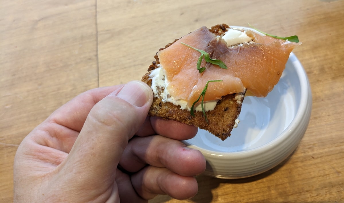 smoked salmon on crackers with creme being held in had above plate.
