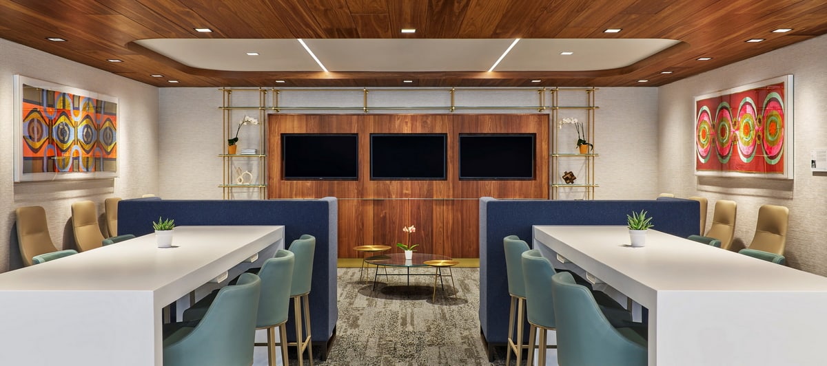 Seating area with chairs, tables, TVs and art.