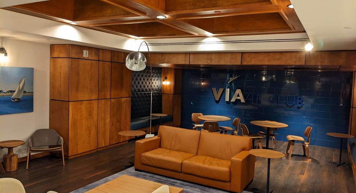 Main seating area inside of the Harlingen VIA VIP Club lounge, with seating tables and art on the walls.