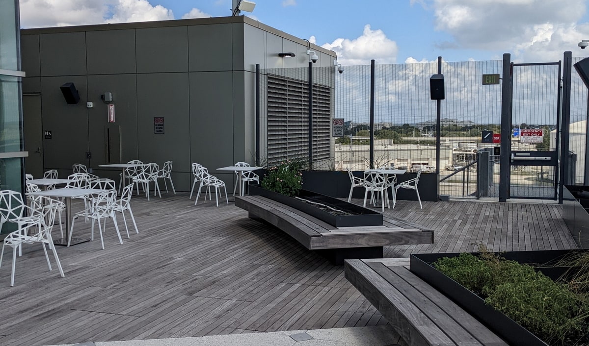 Outdoor patio with a wood deck at the airport with tables and furniture for guests.