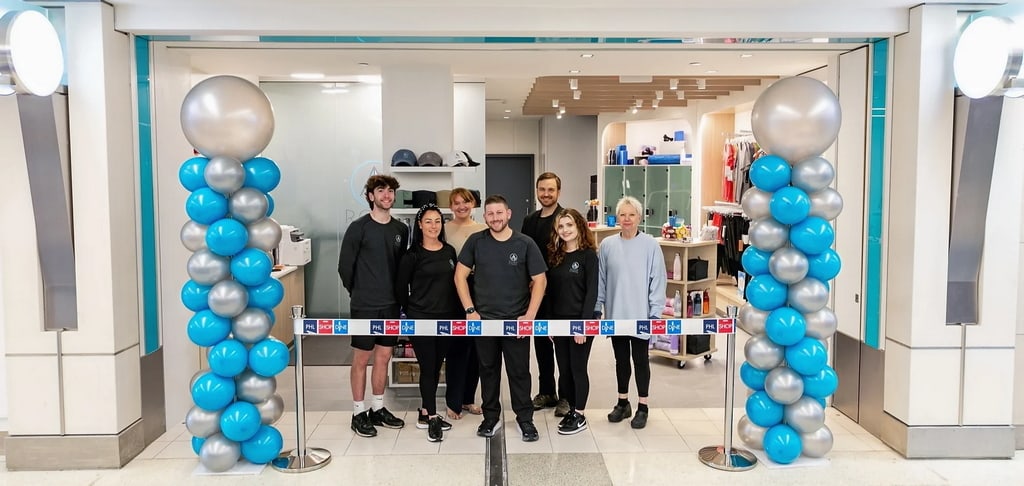 Employees standing at the ROAM Fitness entrance before the ribbon cutting with balloons.