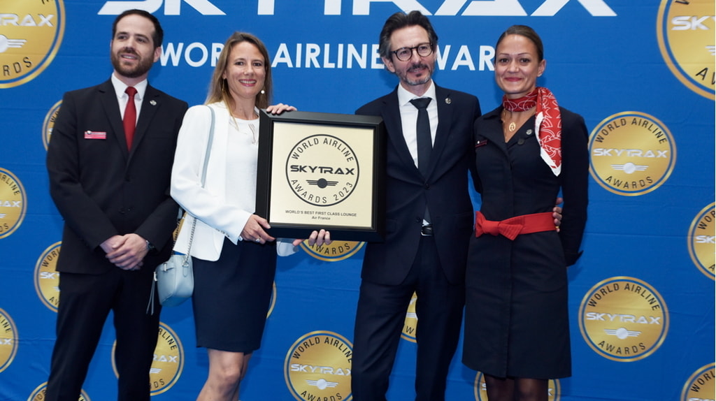 four people standing on the stage holding the award for Worlds Best First Class lounge.