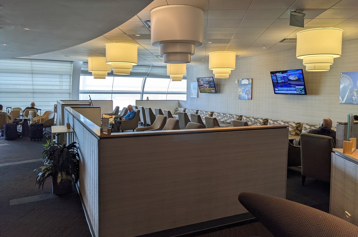 Main seating area inside the lounge with seating, tables, and large windows in the background.
