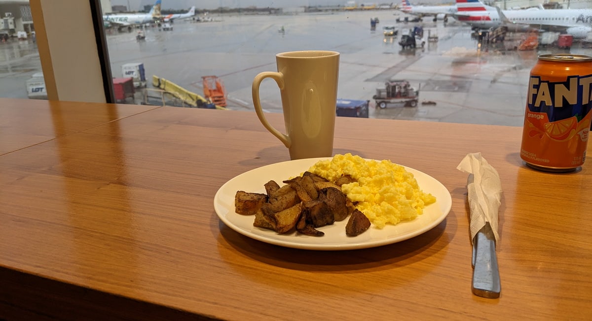 window view of the airport area and a table with eggs and potatoes.