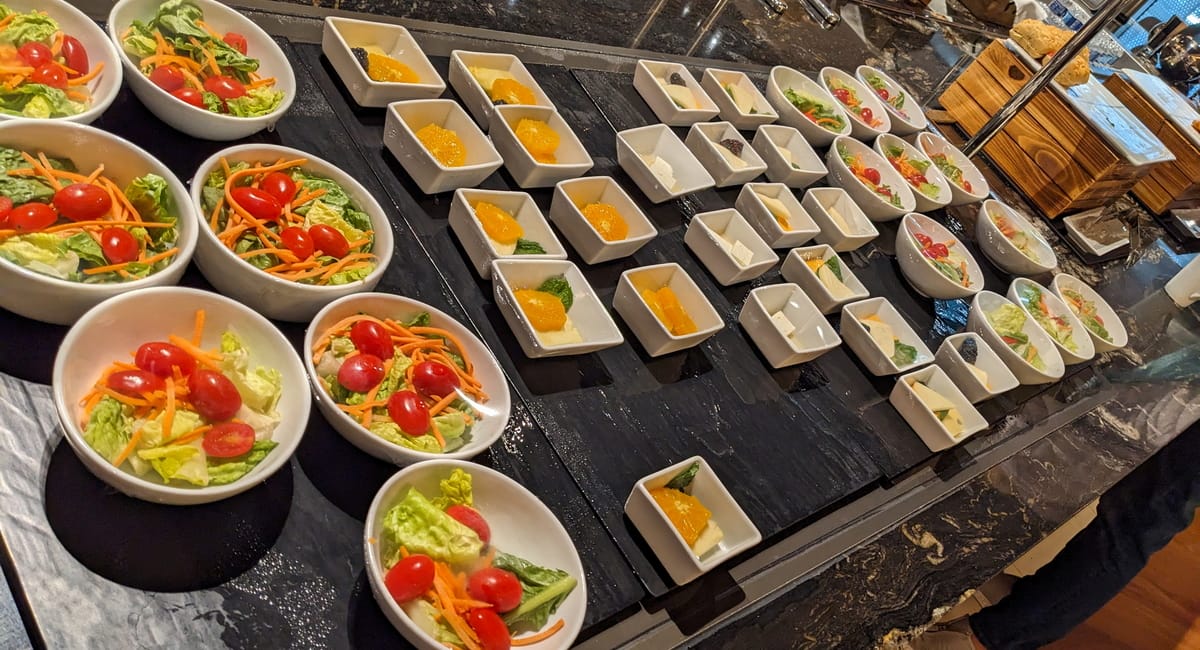 food area with two different types of plated salads, in a self-serve area.