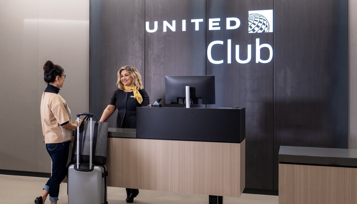 Two people standing at the check-in desk with United Club in the background.