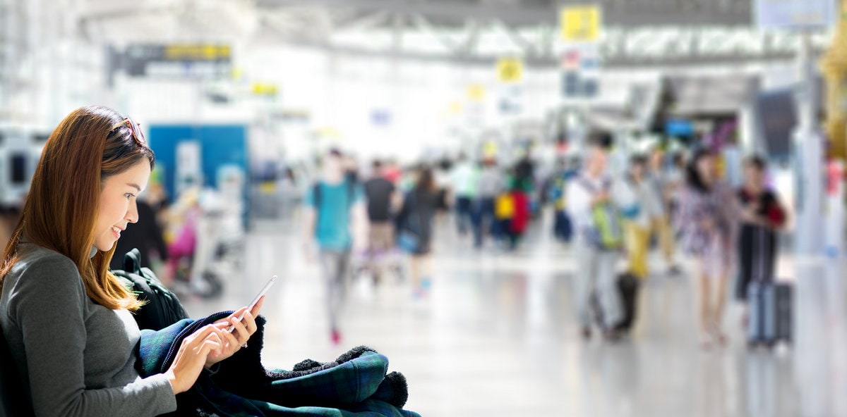 Person sitting in a busy terminal with people walking in the background.