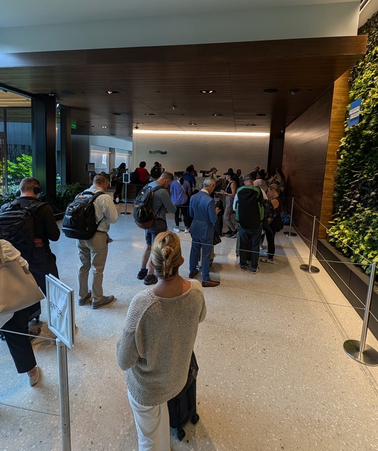 people waiting inside the Centurion Lounge at Atlanta, with green plants on the wall.