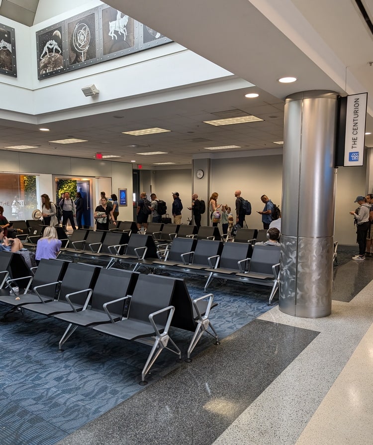 about 25 people waiting in a line outside the Centurion Lounge in Atlanta at the gate.