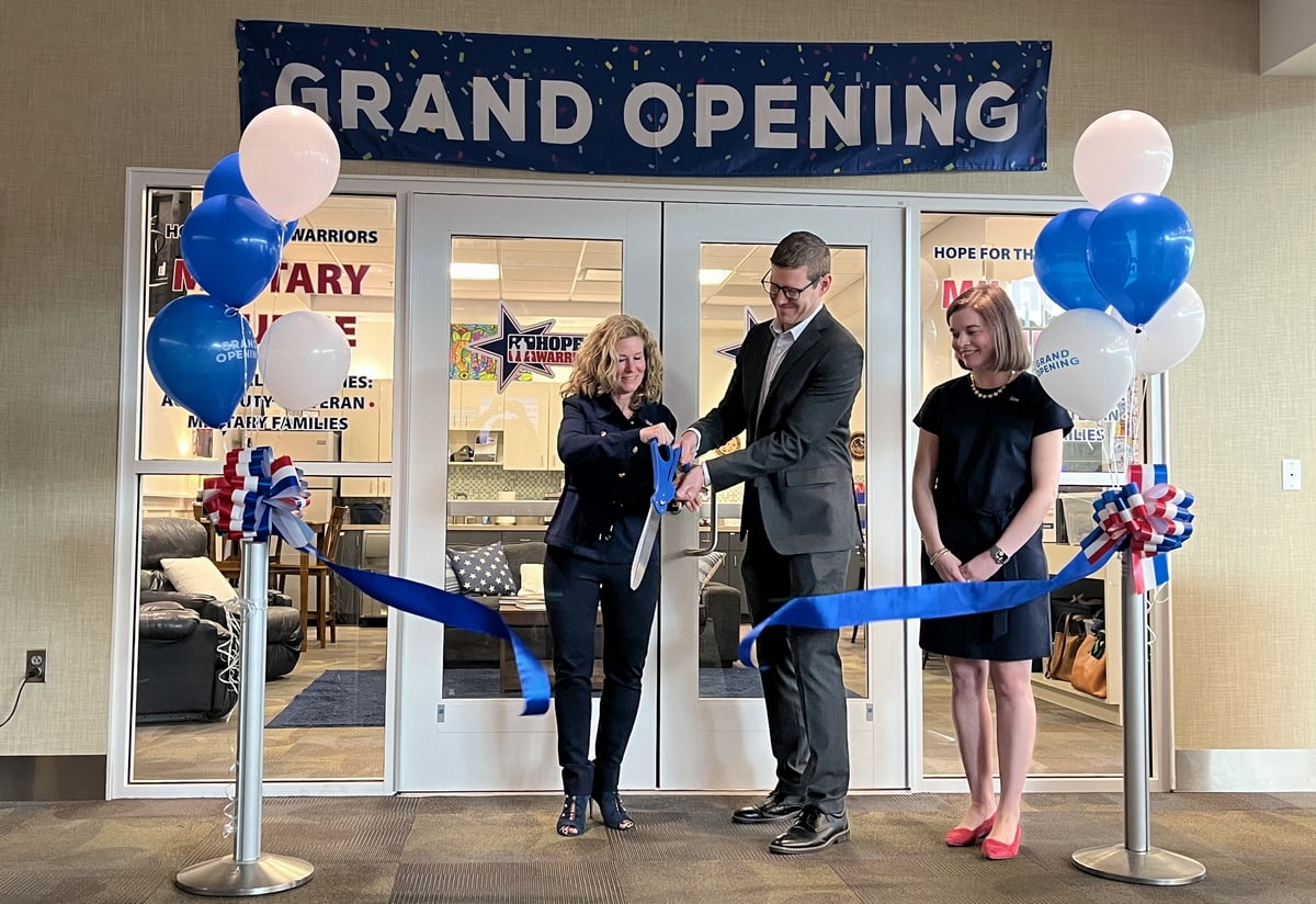 Three people are cutting the ribbon at the grand opening entrance of the lounge.