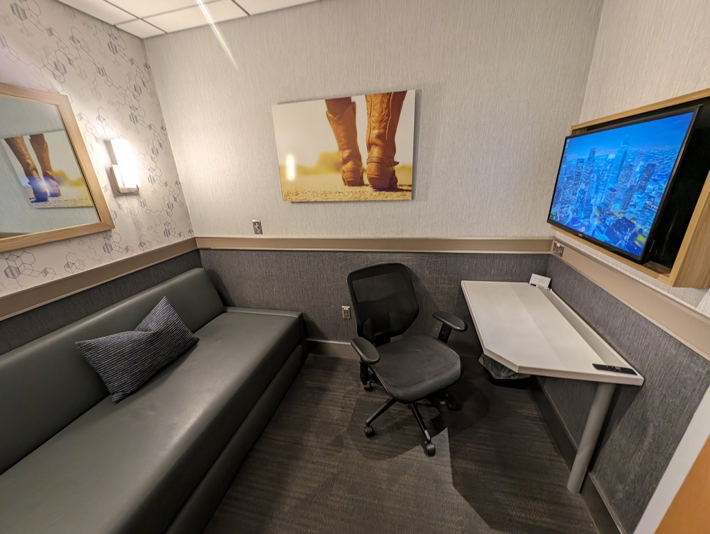 view of the Minute Suites room showing sofa-bed, desk, chair, and TV.