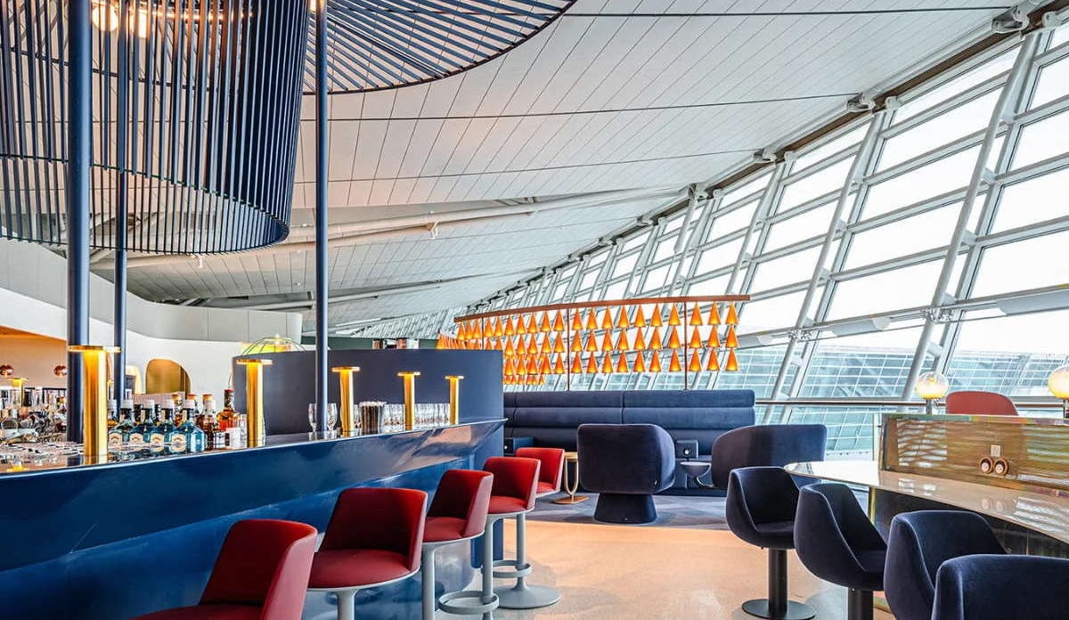 inside view of the oneworld lounge showing bar area, seating, and windows.