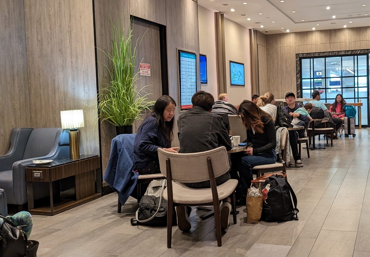 seating area with tables, chairs, and TVs on the wall.