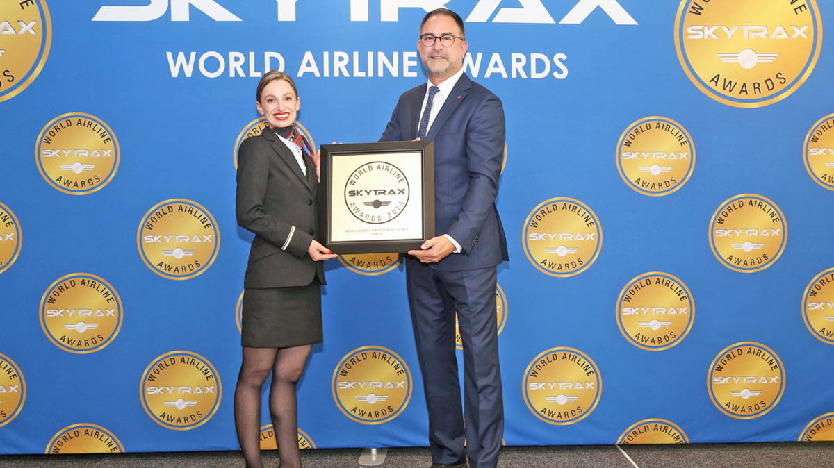Two people holding the award for best first class lounge of 2024.