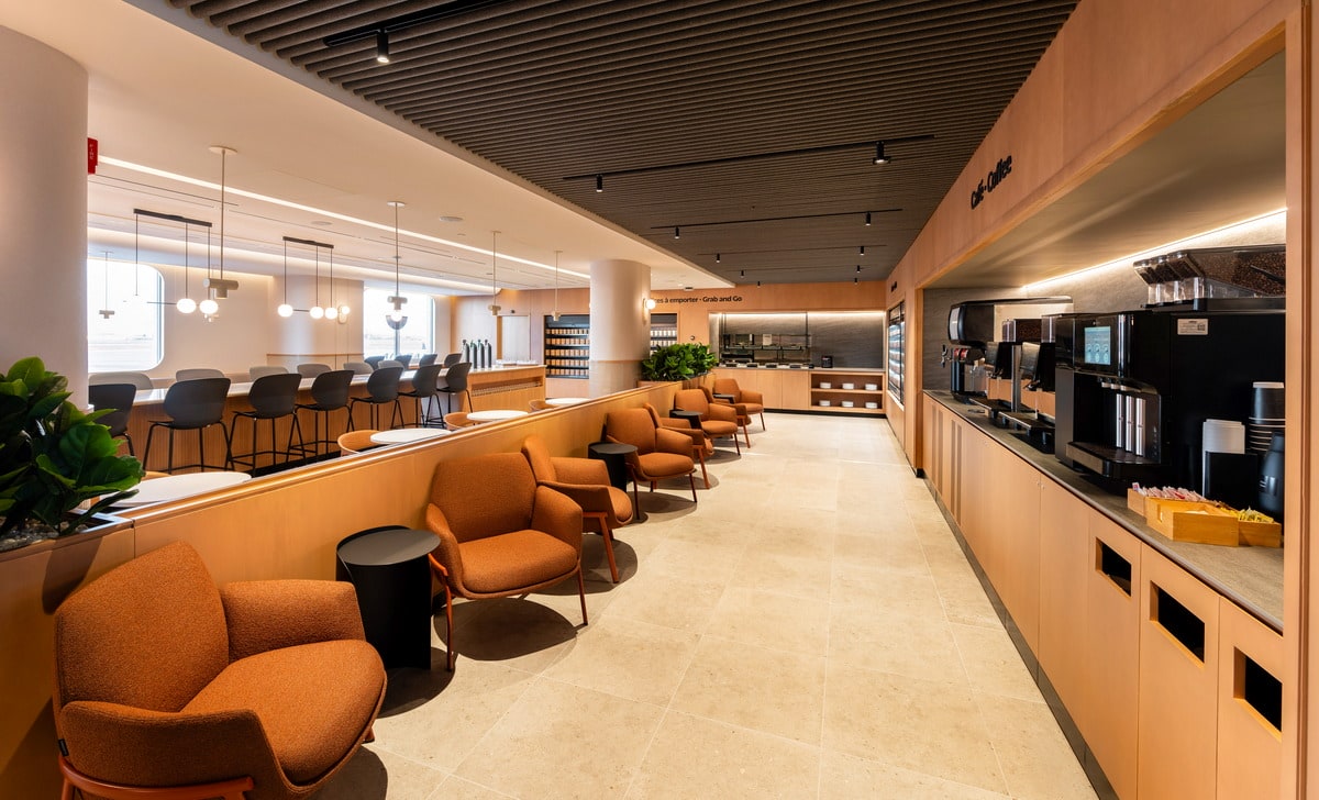 View inside the Cafe lounge, showing seating, coffee area, grab and go section, and windows in the background.