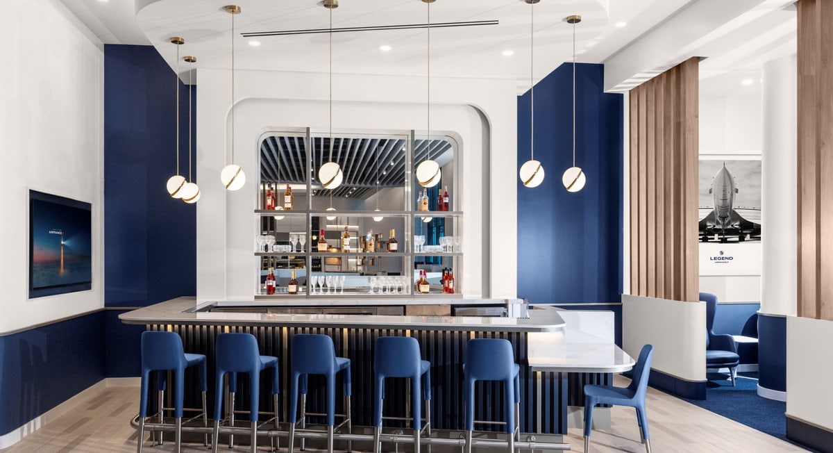 Bar with mirror in the background and blue bar chairs around.