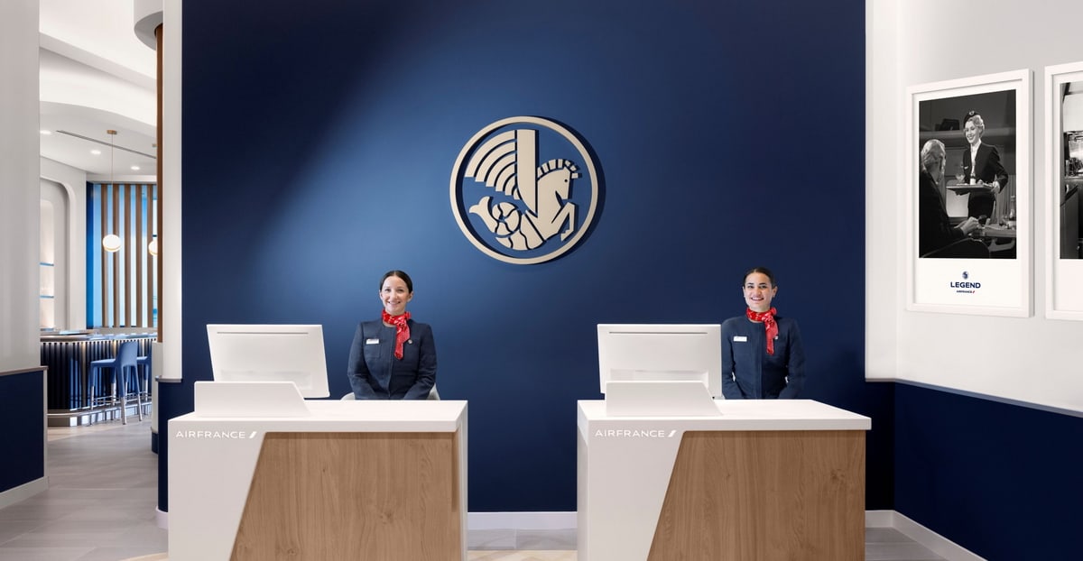 Two people standing behind check-in desk with blue background and air france logo.