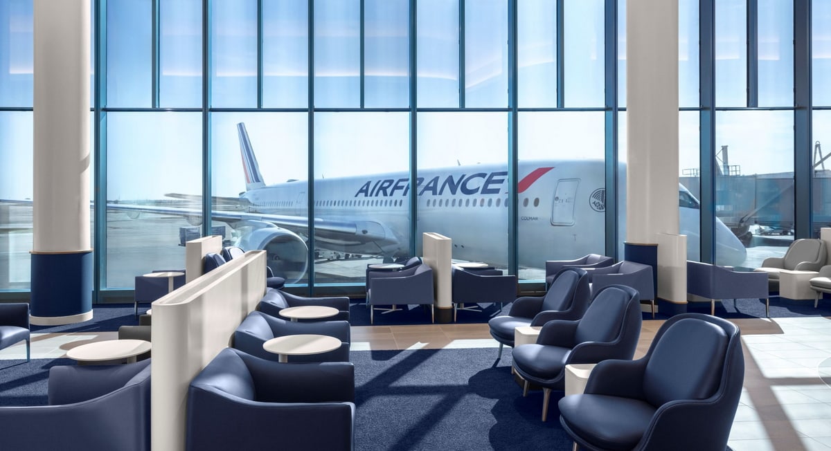main seating area with chairs and small tables, windows with ramp views.