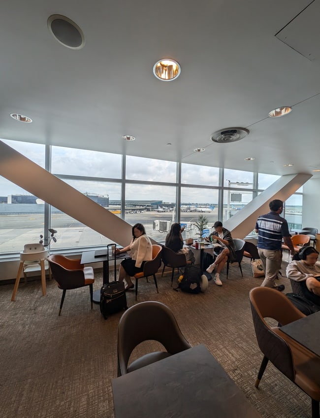 Tables and seating with large windows with views of the airport gates.