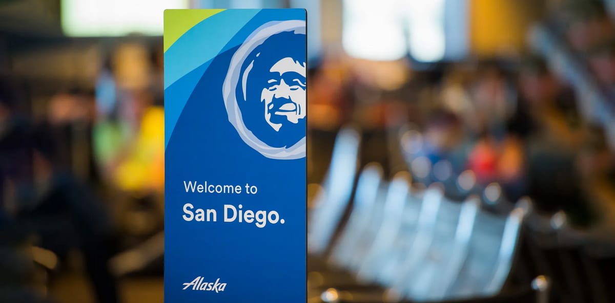 White pamphlet showing Alaska Airlines logo with the writing Welcome to San Diego with faded terminal in the background.