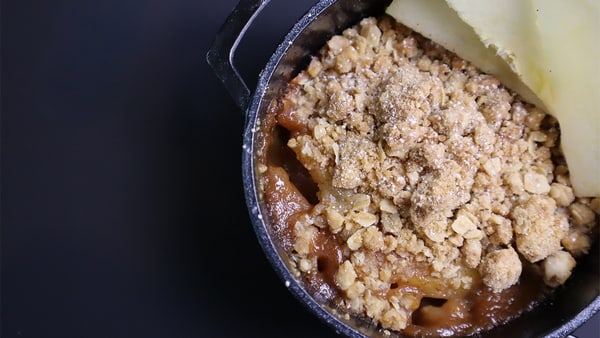 Baked apples with cinnamon and oat topping in a cast iron pan.