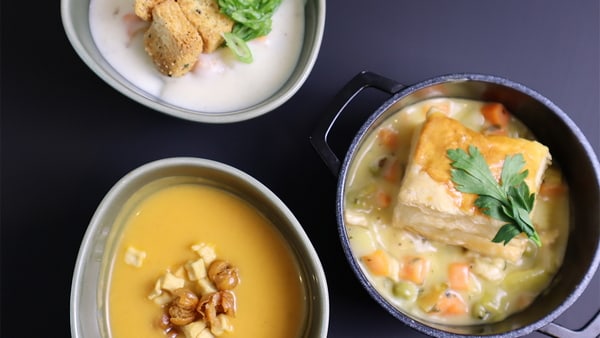 Three bowls with soup and other menu items.