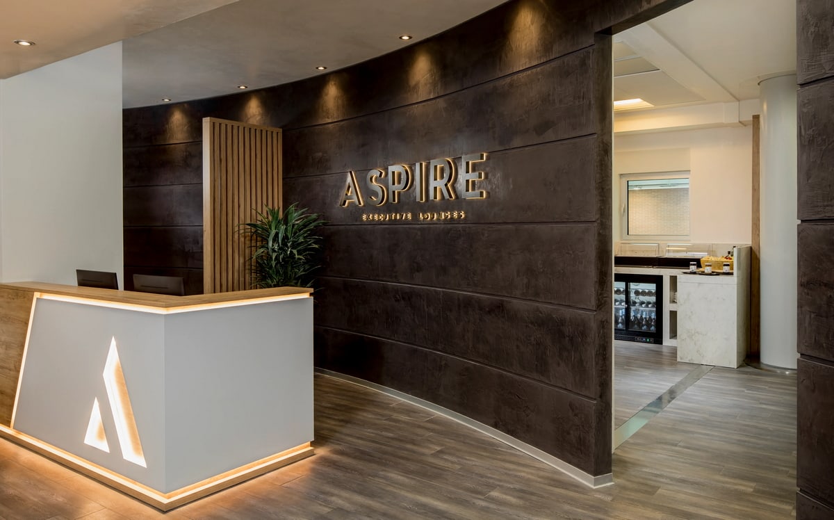 Entrance area and reception desk at Aspire Lounge, with door in background.