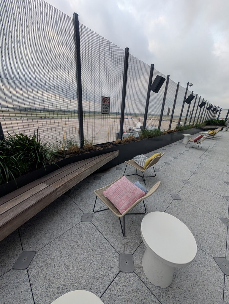 lounge chairs and tables, with view of ramp area and planes.