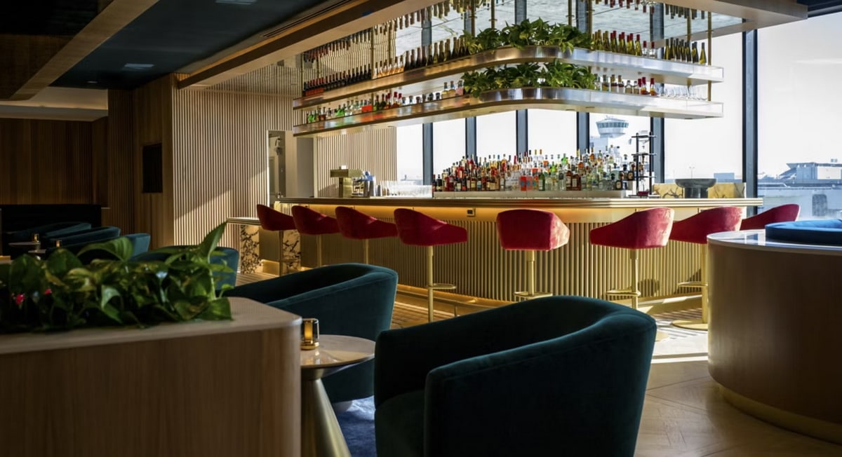 Bar area with chairs and seating arond the bar, with large windows in the background.