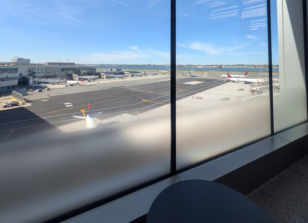 Outside patio with a view out the windows of airplanes and water in the background.