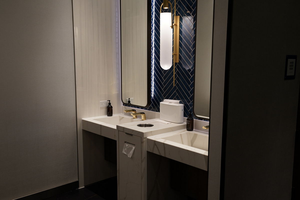 marble sink area with soap and windows in the mens restroom.