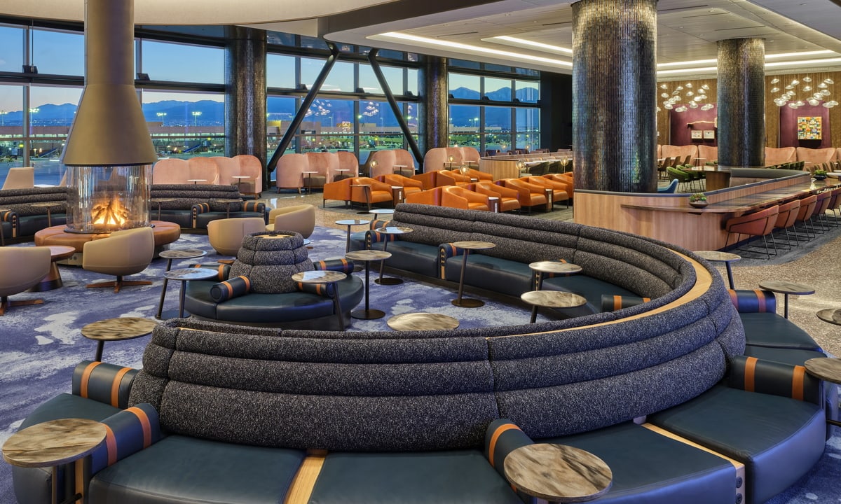 Delta lounge seating area and fireplace and chairs, large windows and mountains in the background.