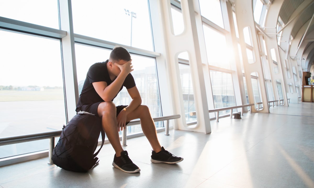 Person sitting near windows in airport terminal, resting.