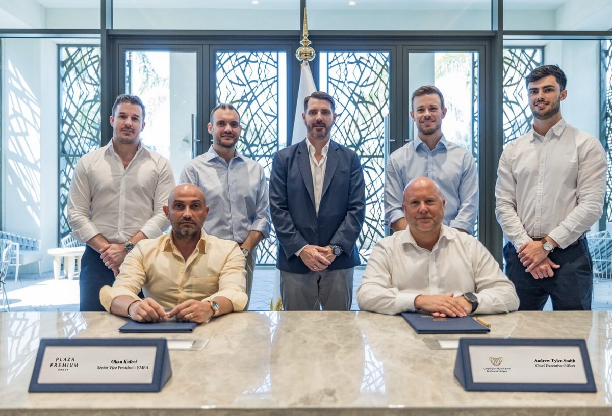 Group of people signing paperwork sitting at a marble table.
