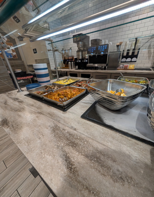 breakfast items, eggs, potatoes, and sausage in serving pans.