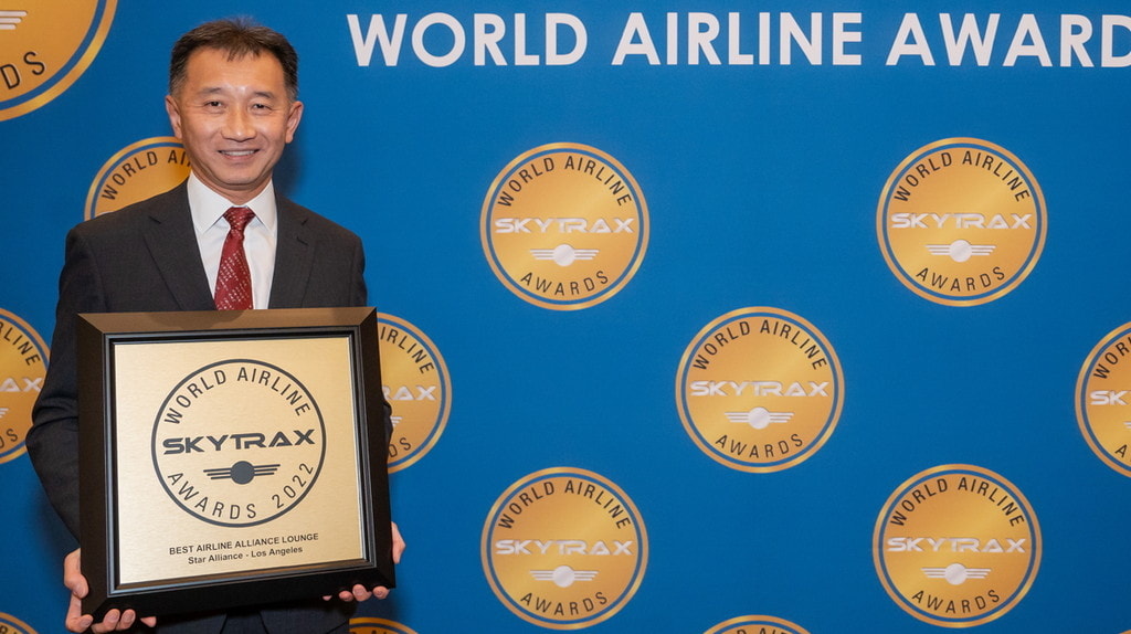 person holding an award, that reads the Best Airline Alliance lounge.