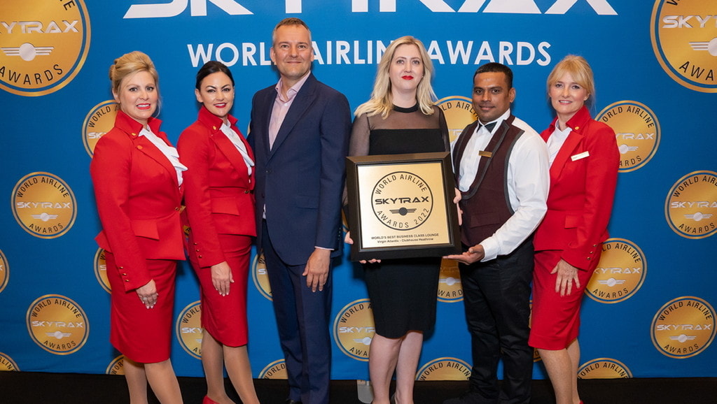 people posing with award for best business class lounge.