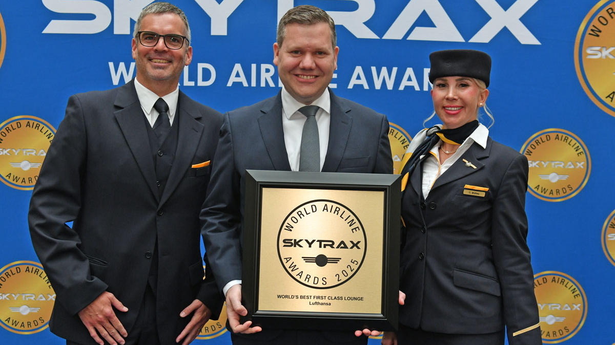 Three people holding the award for best First Class lounge, with a SKYTRAX World Airline Awards banner in the backround.