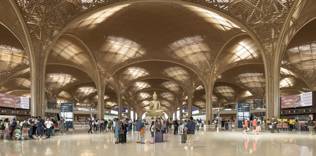 Main arrivals area with large buddha statue and people waiting to checking.